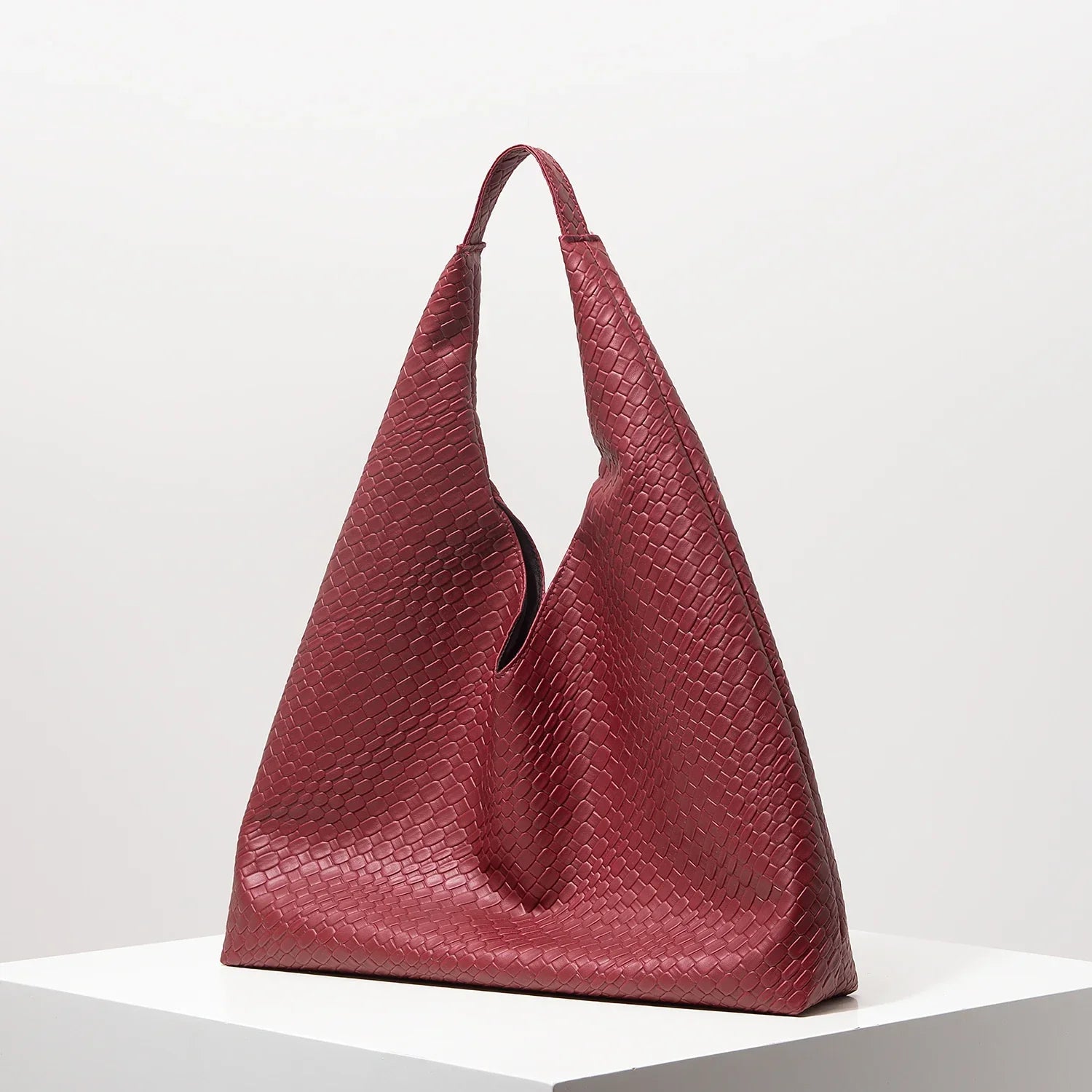 Bolsa feminina vermelha de couro texturizado, formato triangular, elegante em fundo branco.