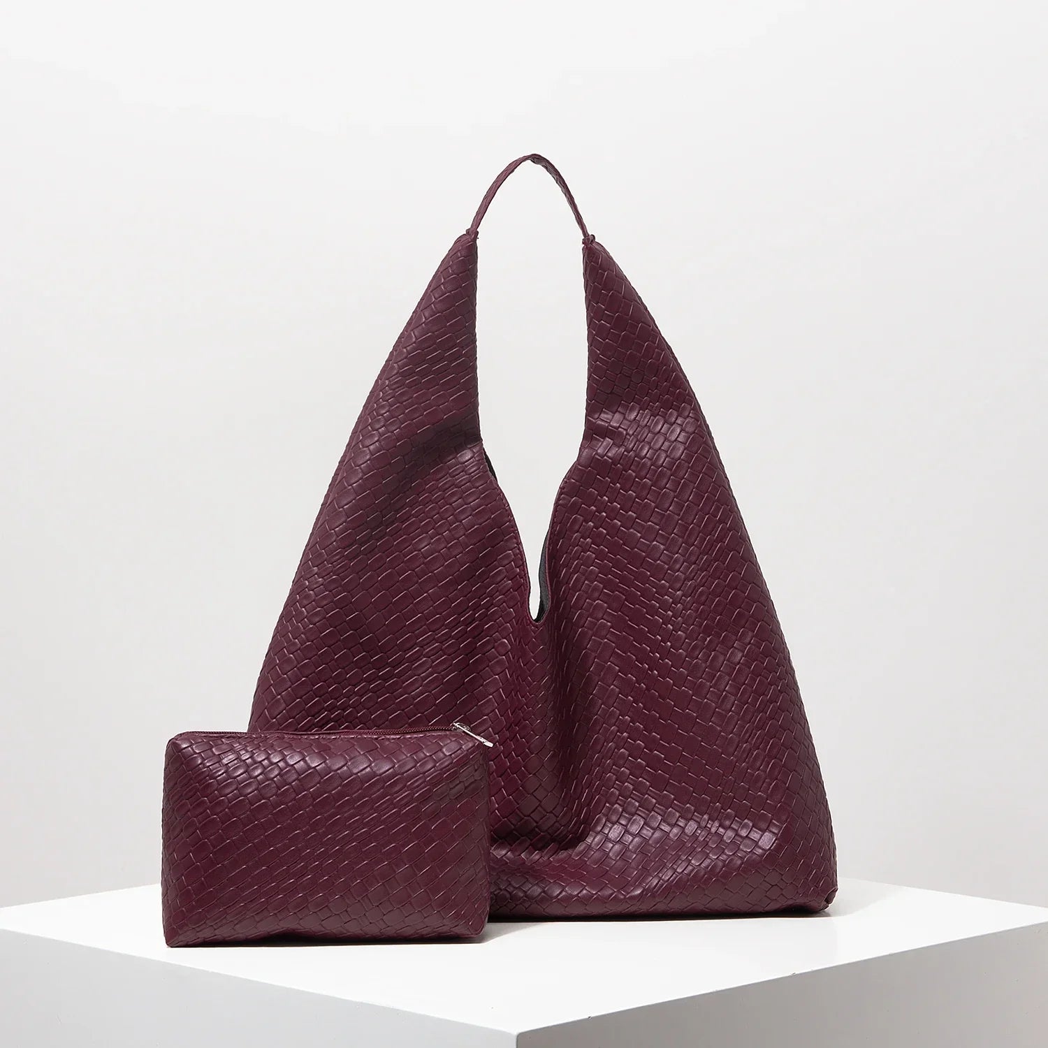 Bolsa feminina roxa de couro texturizado e nécessaire combinando sobre base branca