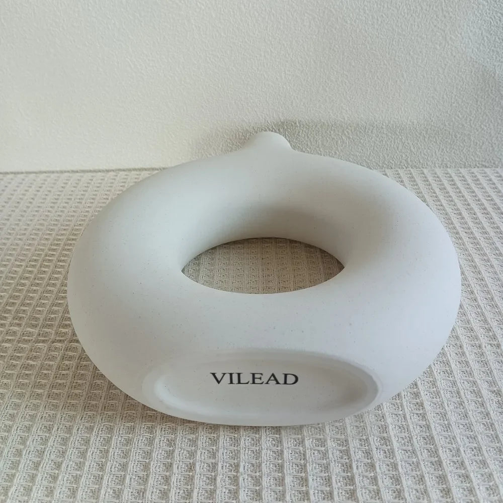 Vaso decorativo de cerâmica branco em formato circular com a marca VILEAD, sobre superfície texturizada.