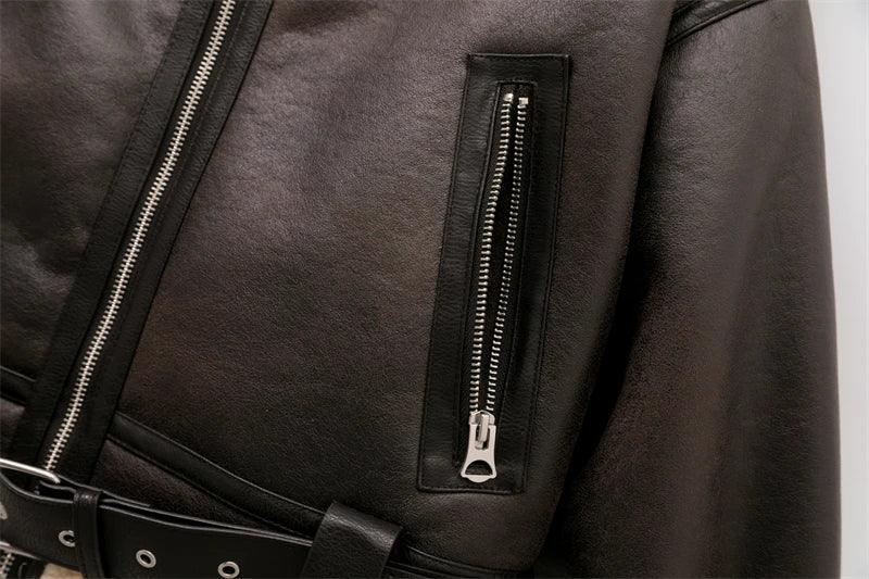 Detalhe de jaqueta de couro preta com zíper e cinto prateado
