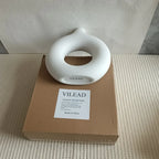 Vaso cerâmico em formato de donut VILEAD branco sobre caixa marrom, decoração minimalista