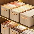 Caixas organizadoras bege em prateleira de madeira com roupas dobradas e organizadas.