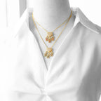 Colar duplo dourado com pingentes detalhados sobre camisa branca feminina